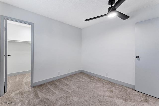 unfurnished bedroom with a spacious closet, carpet flooring, baseboards, and a textured ceiling