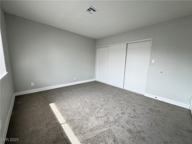 unfurnished bedroom featuring visible vents, baseboards, carpet, and a closet