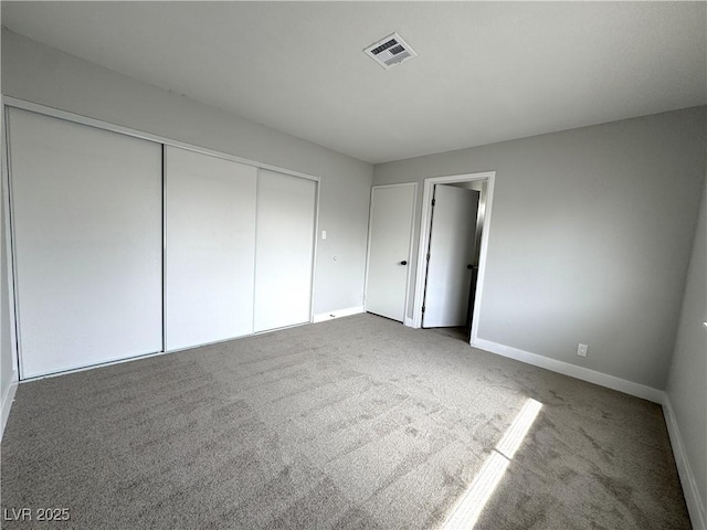 unfurnished bedroom with carpet, visible vents, a closet, and baseboards