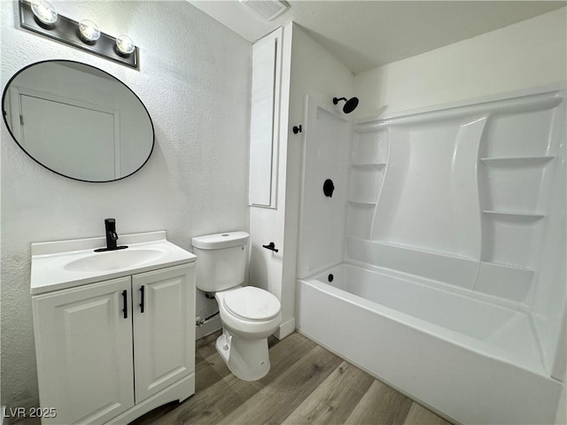 full bathroom with visible vents, toilet, wood finished floors, vanity, and shower / bathtub combination