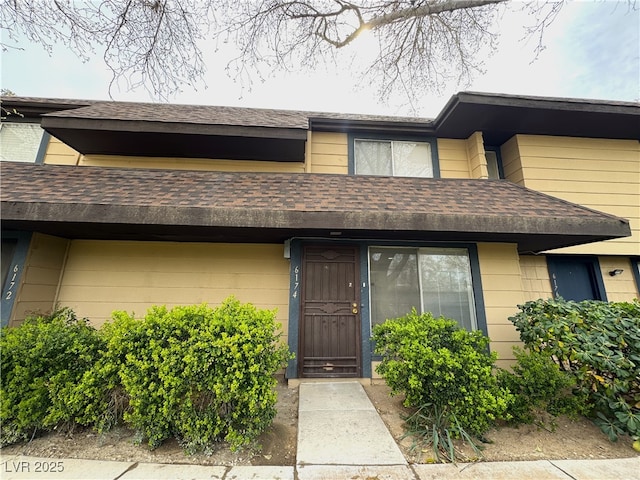 doorway to property with roof with shingles