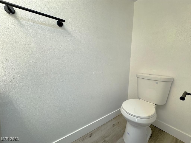 bathroom with baseboards, toilet, and wood finished floors