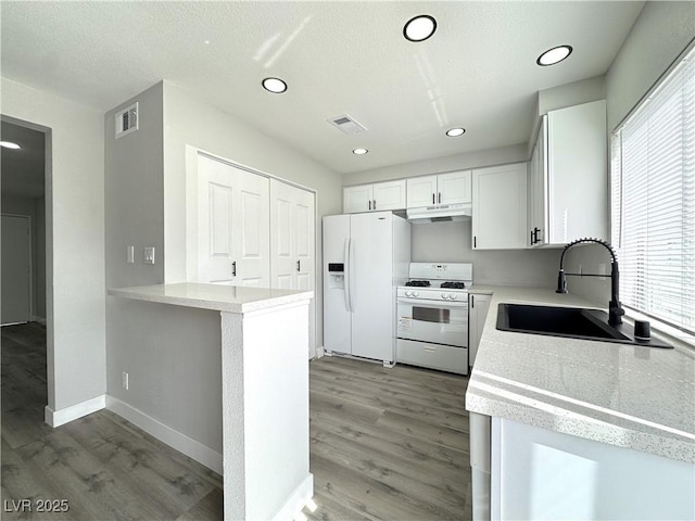 kitchen with white appliances, visible vents, a sink, white cabinets, and under cabinet range hood