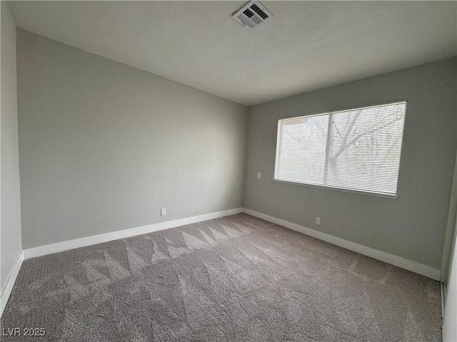 empty room featuring carpet flooring, baseboards, and visible vents