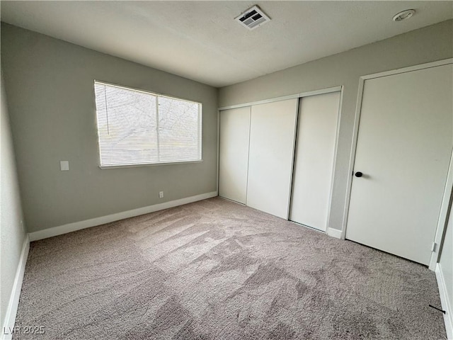 unfurnished bedroom with carpet, visible vents, a closet, and baseboards