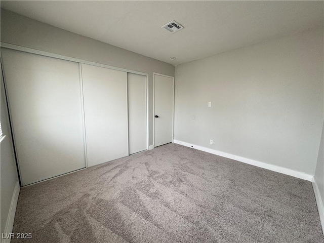 unfurnished bedroom with a closet, visible vents, carpet flooring, and baseboards