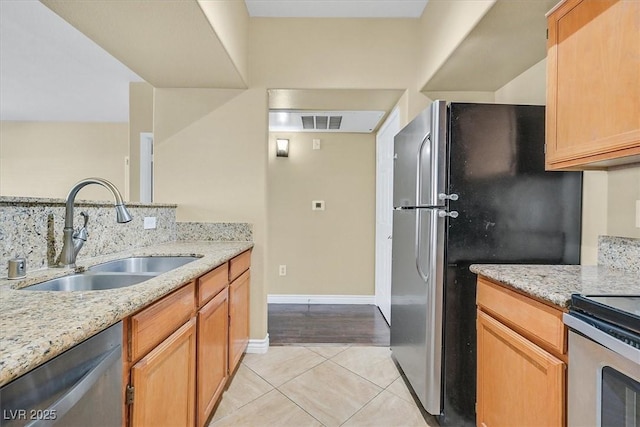 kitchen with light stone counters, light tile patterned floors, visible vents, a sink, and appliances with stainless steel finishes