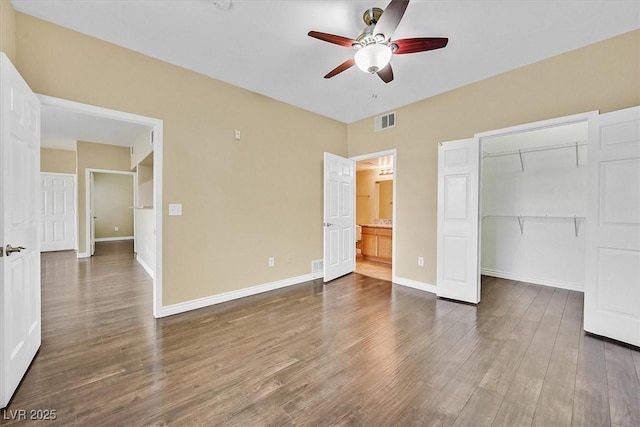 unfurnished bedroom featuring baseboards, visible vents, dark wood-style flooring, a spacious closet, and a closet