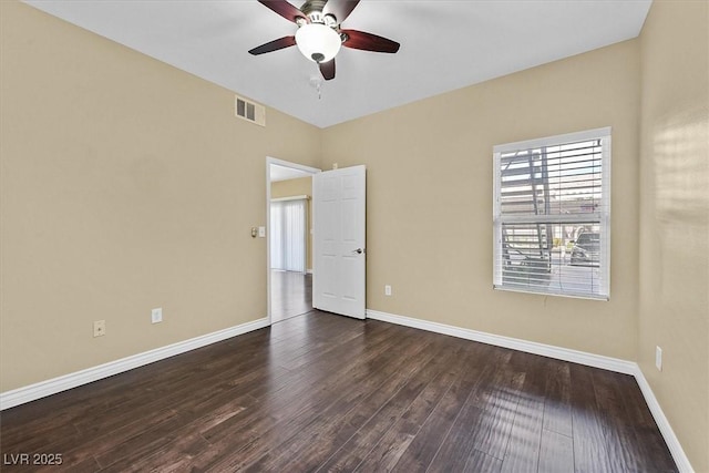 spare room with wood finished floors, a ceiling fan, visible vents, and baseboards