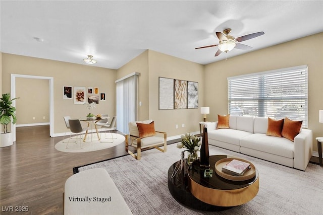 living area featuring wood finished floors, baseboards, and ceiling fan