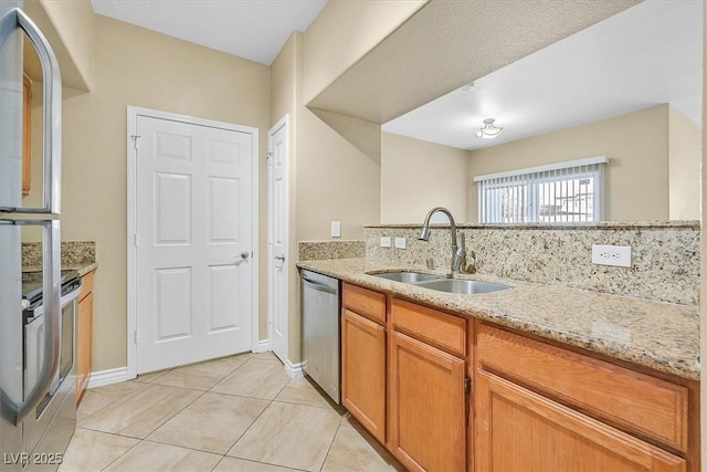 kitchen featuring a sink, stainless steel appliances, brown cabinetry, light tile patterned floors, and light stone countertops