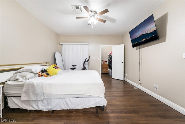 bedroom with a ceiling fan, wood finished floors, visible vents, baseboards, and a spacious closet