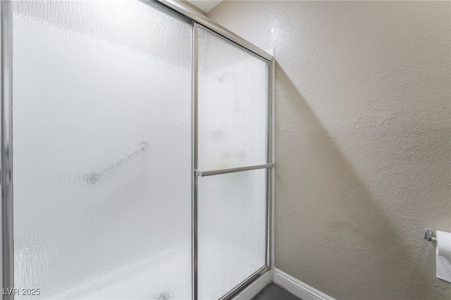 full bath featuring an enclosed shower and a textured wall