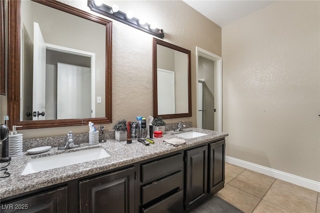 full bathroom featuring a sink, baseboards, double vanity, and tile patterned flooring