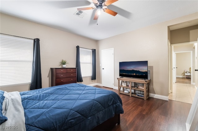 bedroom featuring ceiling fan, visible vents, baseboards, and wood finished floors