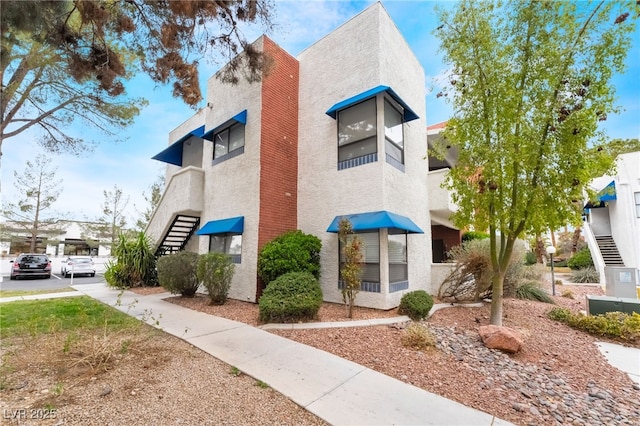 view of side of property featuring stucco siding and stairs