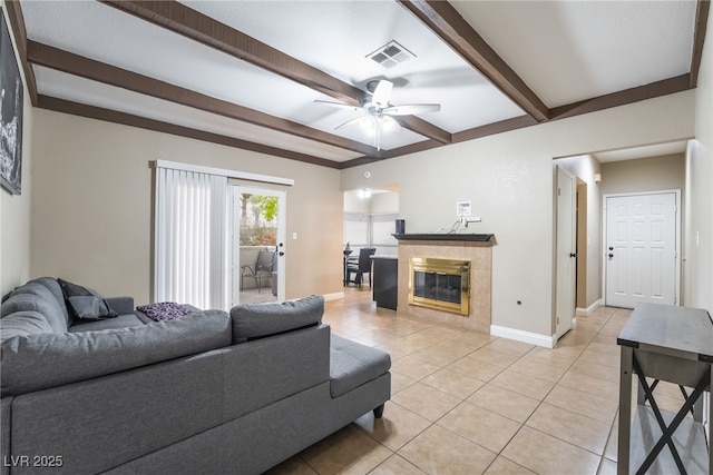 living area featuring visible vents, a tiled fireplace, beam ceiling, light tile patterned flooring, and a ceiling fan