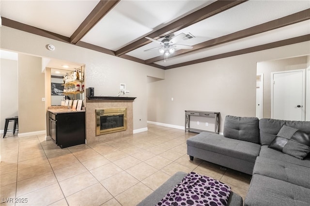 living area featuring light tile patterned floors, visible vents, baseboards, ceiling fan, and beamed ceiling