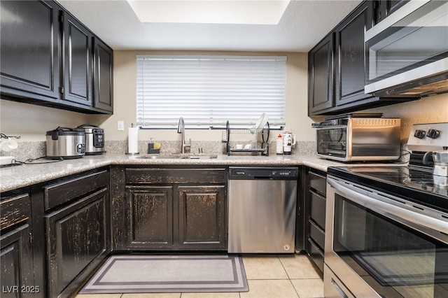 kitchen featuring a toaster, light countertops, light tile patterned flooring, stainless steel appliances, and a sink