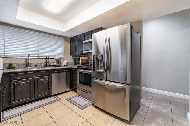 kitchen featuring a sink, stainless steel appliances, a raised ceiling, and light tile patterned flooring