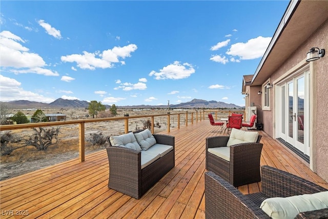 wooden deck with an outdoor living space, a mountain view, and french doors