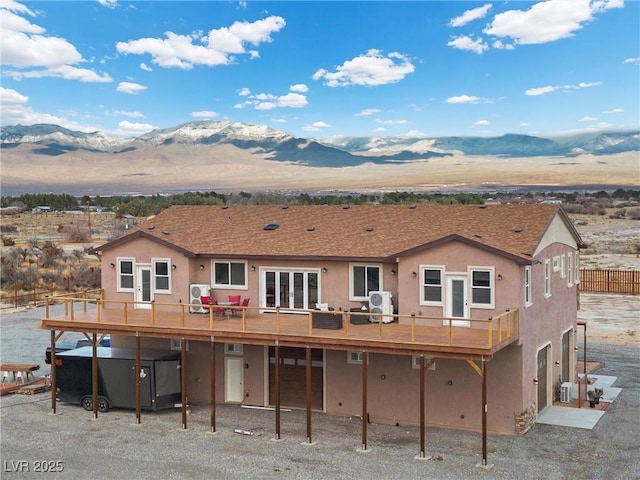 rear view of house with a deck with mountain view, french doors, and stucco siding