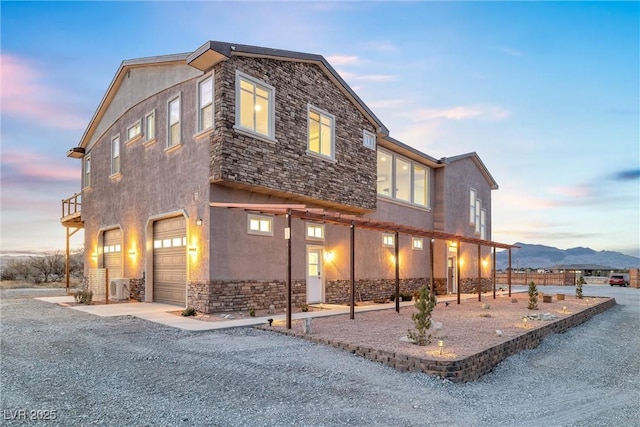 view of front of house with stone siding, stucco siding, and an attached garage