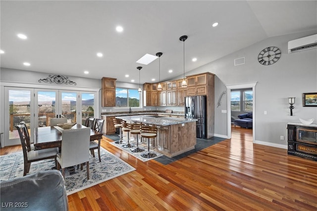 kitchen featuring wood finished floors, stainless steel fridge with ice dispenser, an AC wall unit, glass insert cabinets, and a center island