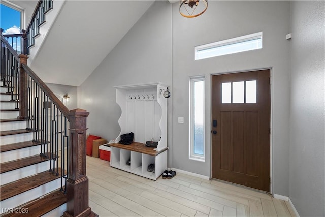 entryway featuring stairway, wood finished floors, baseboards, and high vaulted ceiling