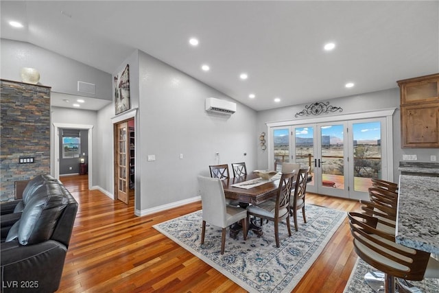 dining space featuring light wood-style flooring, french doors, a wall mounted AC, and lofted ceiling