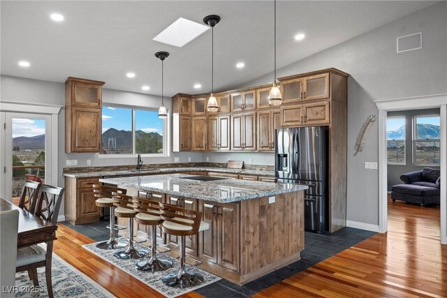 kitchen featuring a sink, dark wood-type flooring, stainless steel refrigerator with ice dispenser, a kitchen bar, and a center island