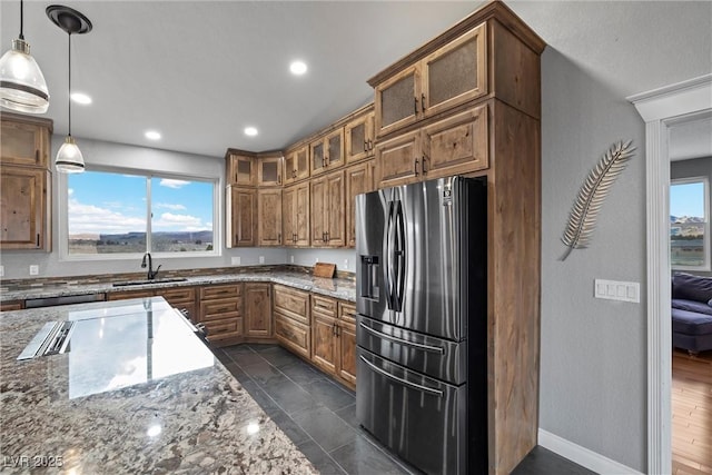 kitchen featuring plenty of natural light, brown cabinets, stainless steel refrigerator with ice dispenser, and a sink