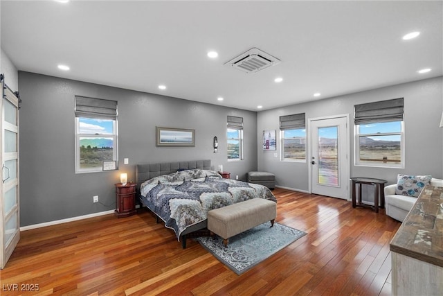 bedroom with visible vents, recessed lighting, hardwood / wood-style flooring, access to exterior, and a barn door