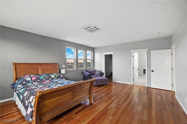 bedroom with visible vents, baseboards, and wood finished floors