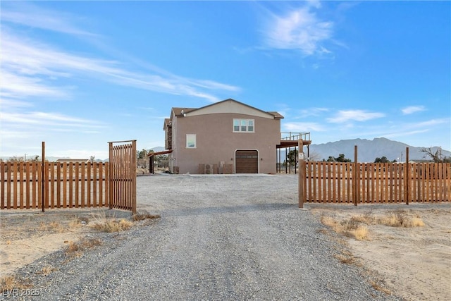 exterior space with gravel driveway, an attached garage, fence, and stucco siding