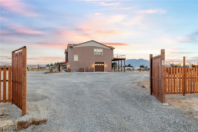 view of side of home with stucco siding, driveway, a garage, and fence