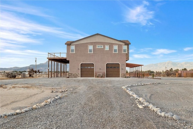 view of front facade with an attached garage, a mountain view, driveway, and stucco siding