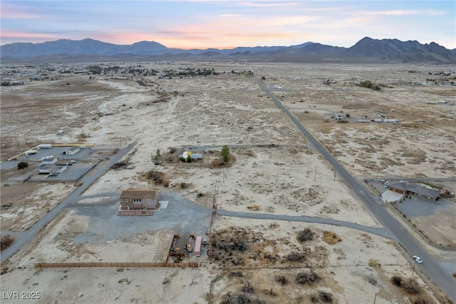 aerial view at dusk featuring a mountain view and view of desert