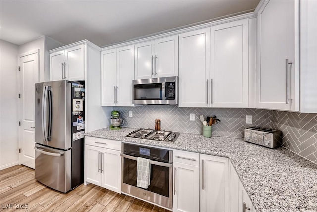 kitchen with stainless steel appliances, light wood-style flooring, decorative backsplash, and white cabinetry