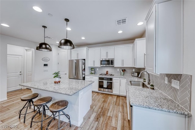 kitchen with a sink, visible vents, appliances with stainless steel finishes, and light wood finished floors