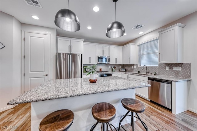 kitchen with a sink, visible vents, appliances with stainless steel finishes, and a breakfast bar