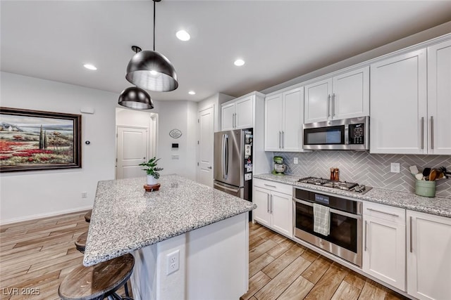 kitchen featuring white cabinetry, tasteful backsplash, light wood-type flooring, and appliances with stainless steel finishes