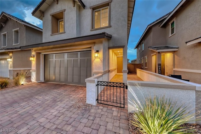 view of front of house featuring stucco siding, driveway, a garage, and fence