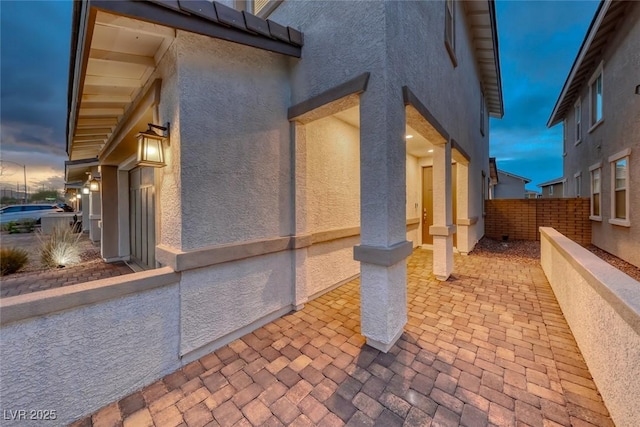 view of side of property featuring a patio area, fence, and stucco siding