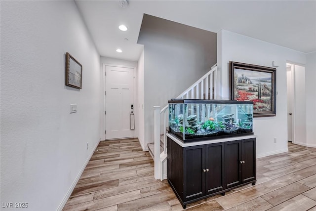 hall featuring recessed lighting, baseboards, light wood-style floors, and stairs