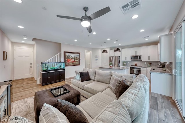 living area featuring recessed lighting, a ceiling fan, visible vents, and light wood finished floors