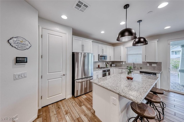 kitchen featuring a kitchen breakfast bar, visible vents, light wood finished floors, and stainless steel appliances