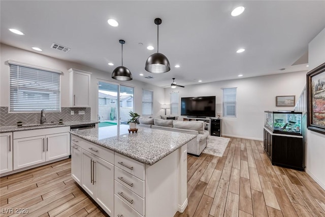 kitchen featuring a sink, visible vents, tasteful backsplash, and light wood finished floors