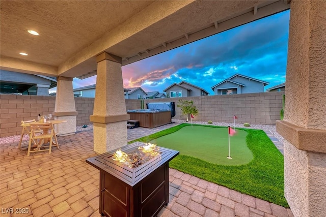 view of patio / terrace with outdoor dining space, a fire pit, a hot tub, and a fenced backyard