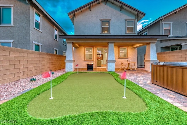 rear view of house with a patio, fence, and stucco siding